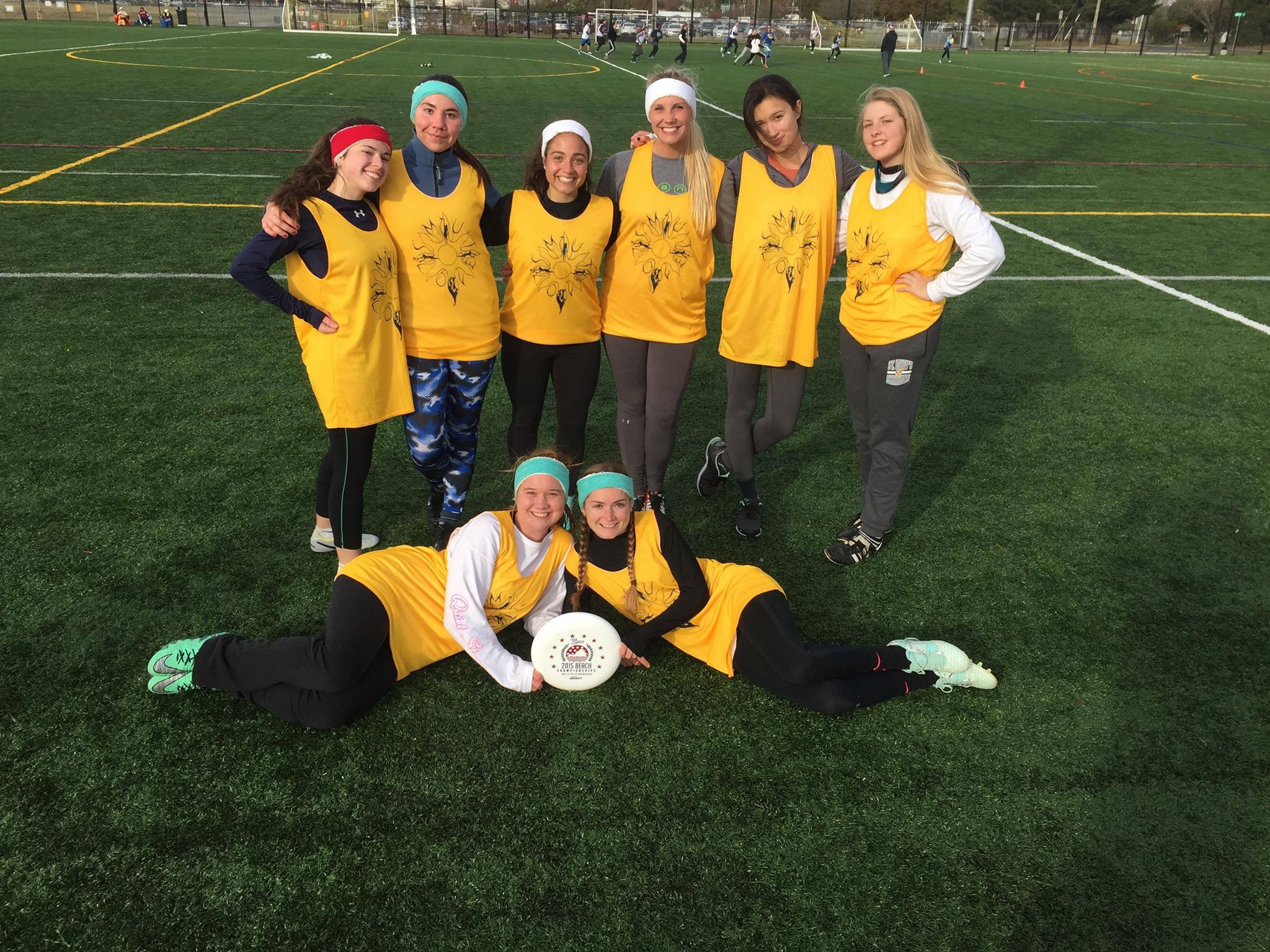The women's ultimate frisbee team poses on a grassy field with a frisbee