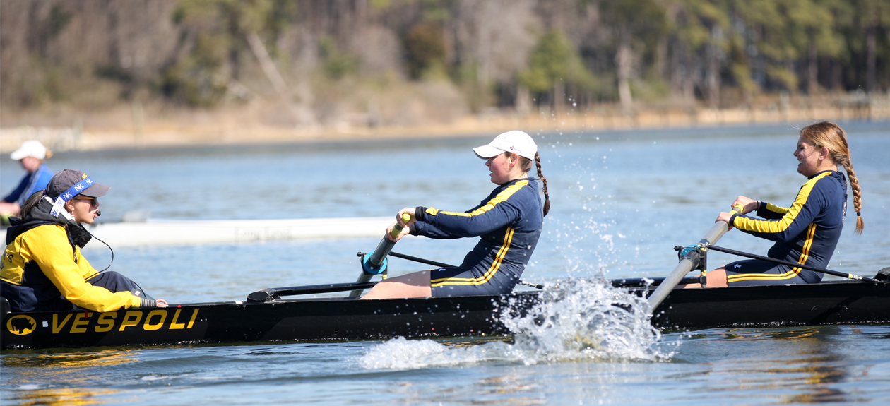 three women in a rowboat on the river.