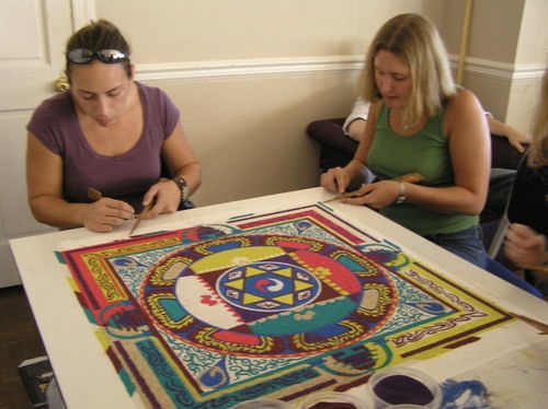 Two students using the chak-pur to place sand of the mandala design.
