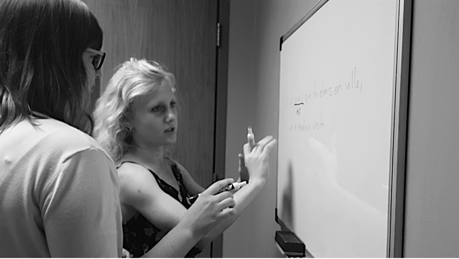 Black and white photo of a peer tutor and student using a whiteboard