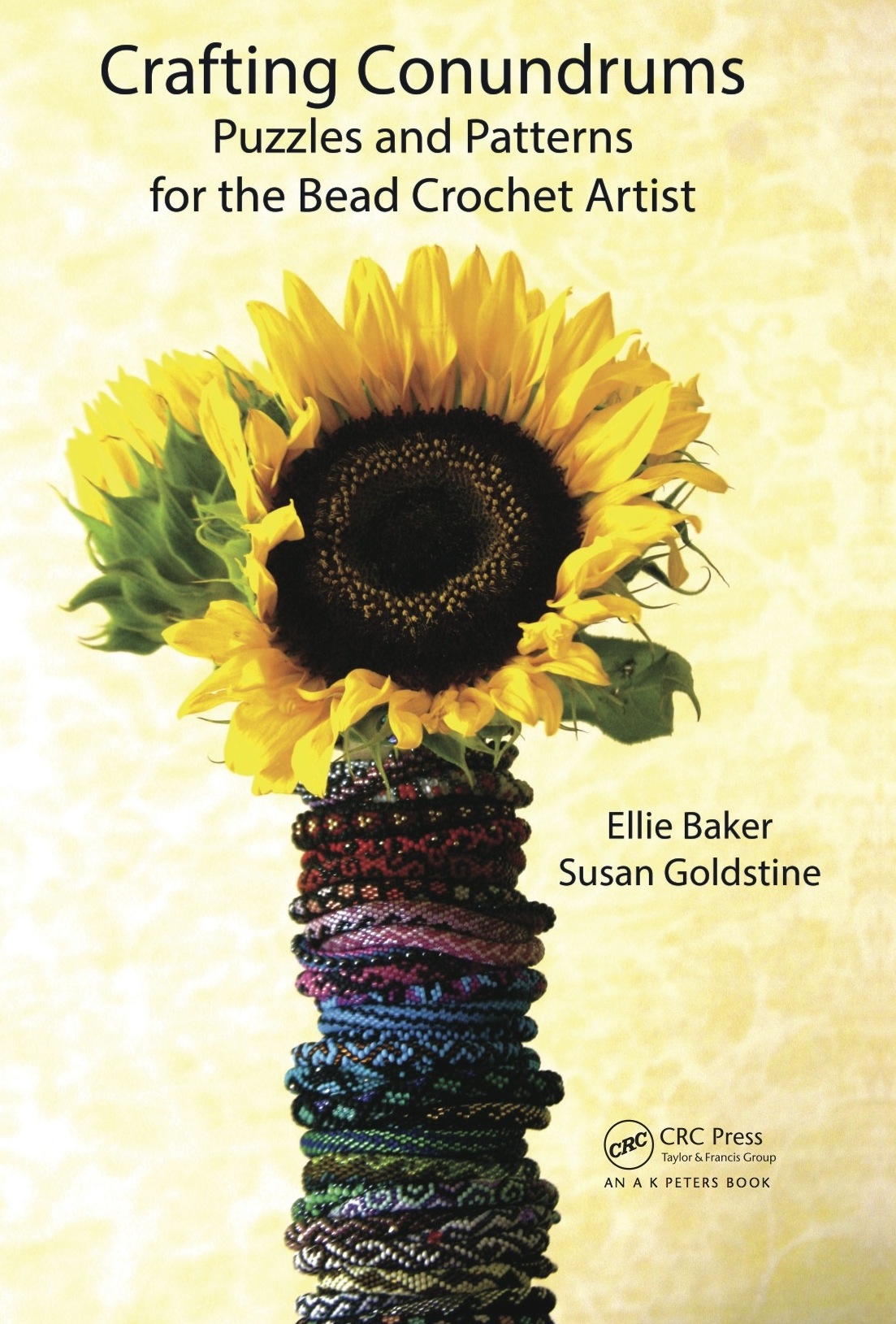 Front cover of Crafting Conundrums, featuring a sunflower atop a stack of beaded bracelets.