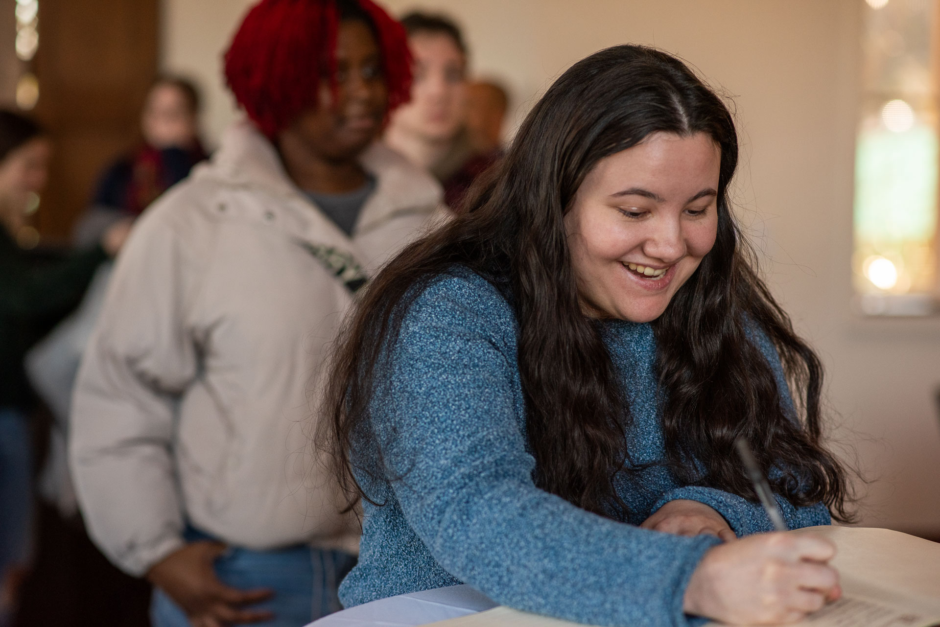 Student signing the President's Book with line of students behind her.