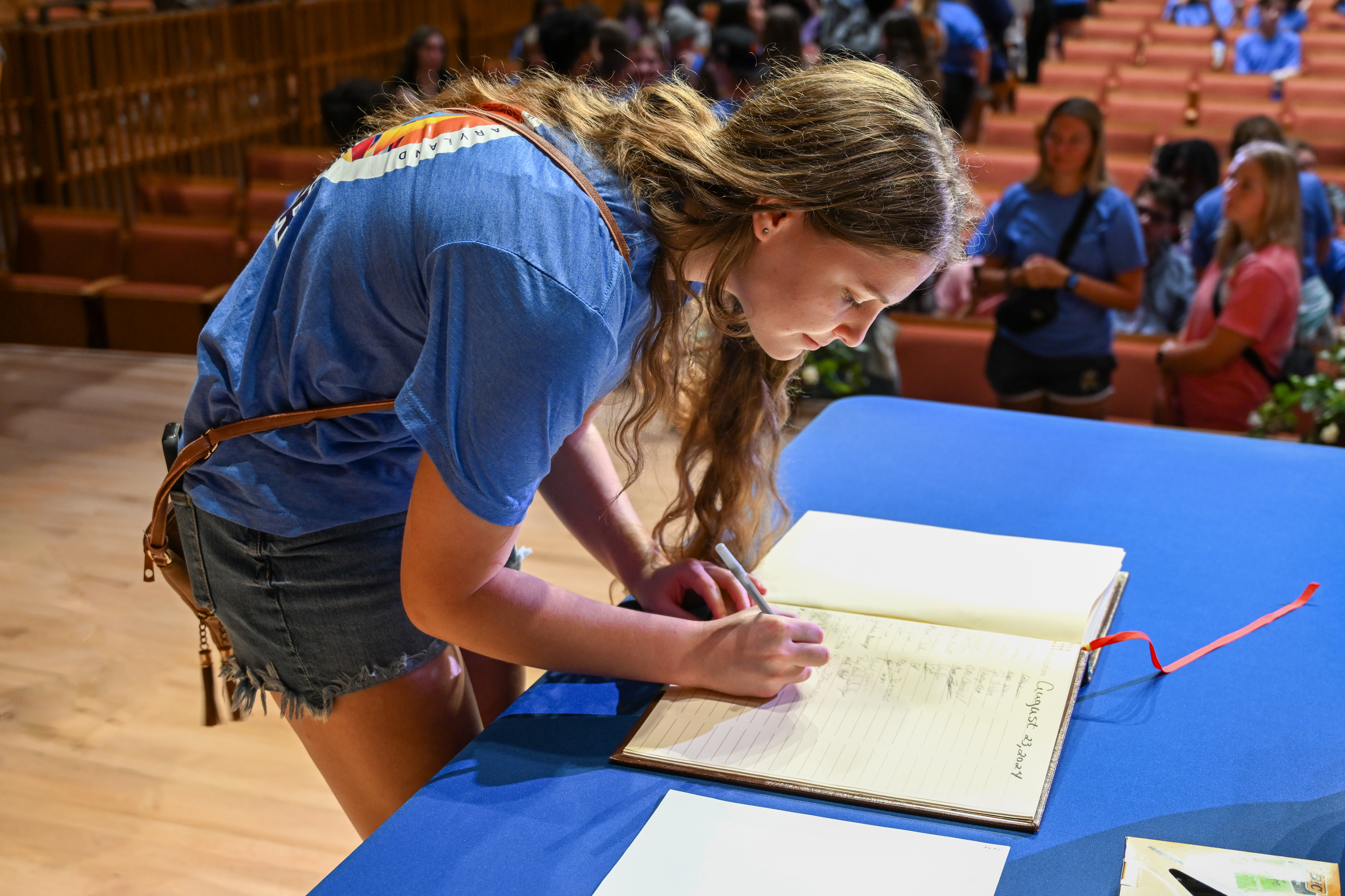 woman signs a book on stage 