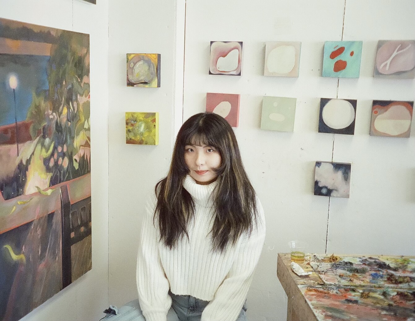 Sitting woman with paintings in background