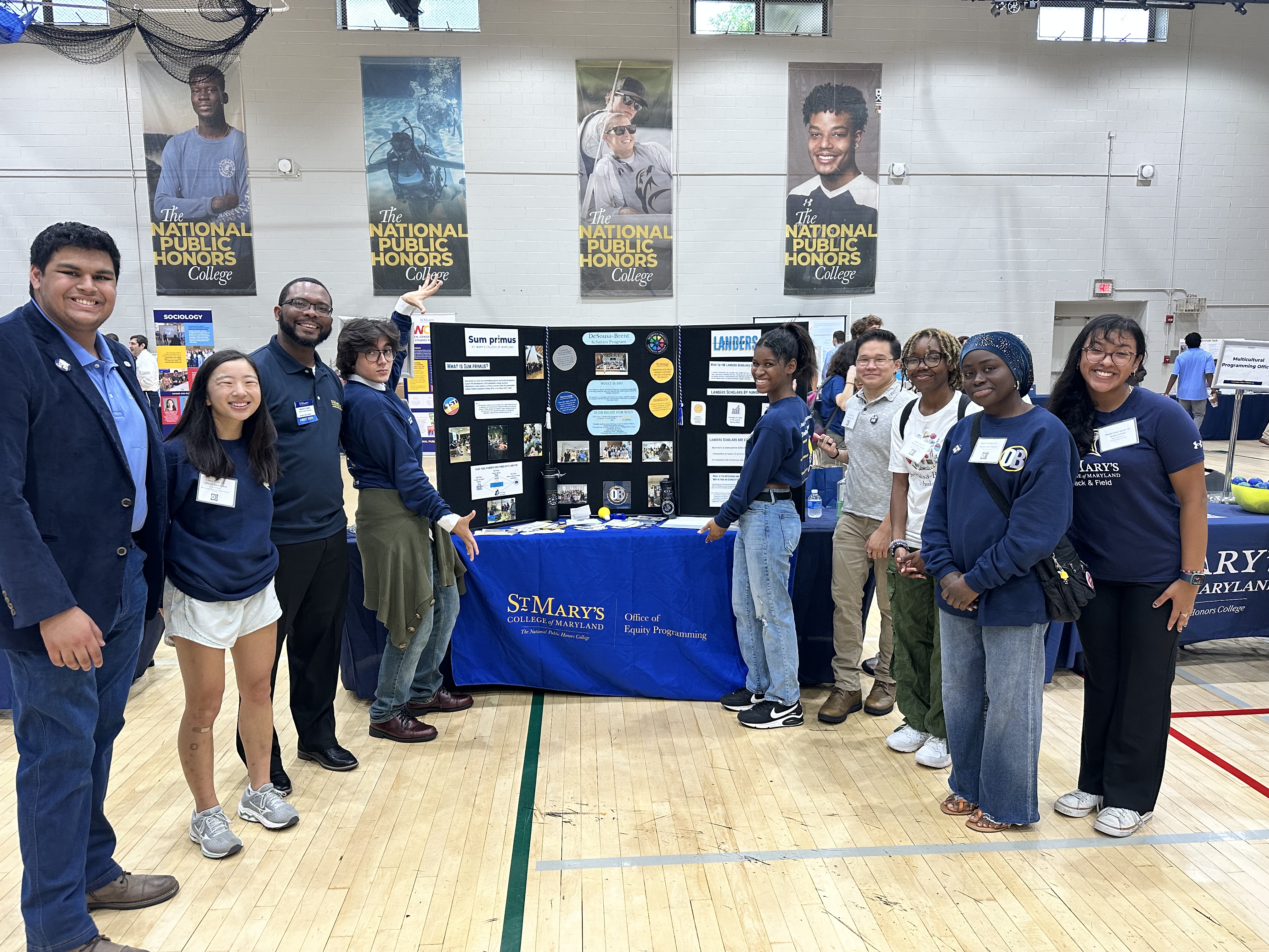 Four people standing on the left of the Office of Equity Programming table and five people standing on the right side of the table during the September 21st Open House