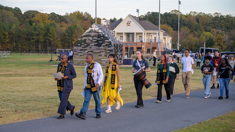 Several people and a drummer walking before the Commemorative to Enslaed Peoples of Southern Maryland