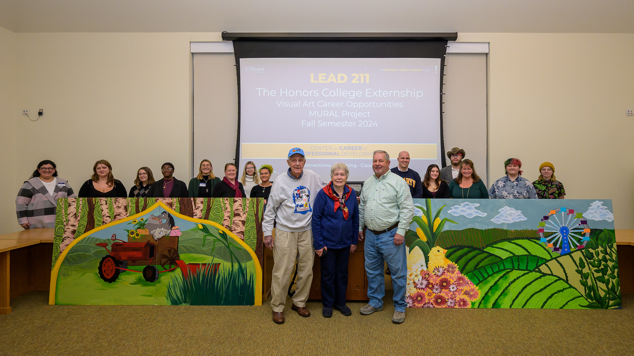 Students, staff and community members surround murals