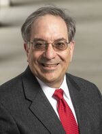 Steohen Zaccaro wearing dark suit, red necktie, and glasses