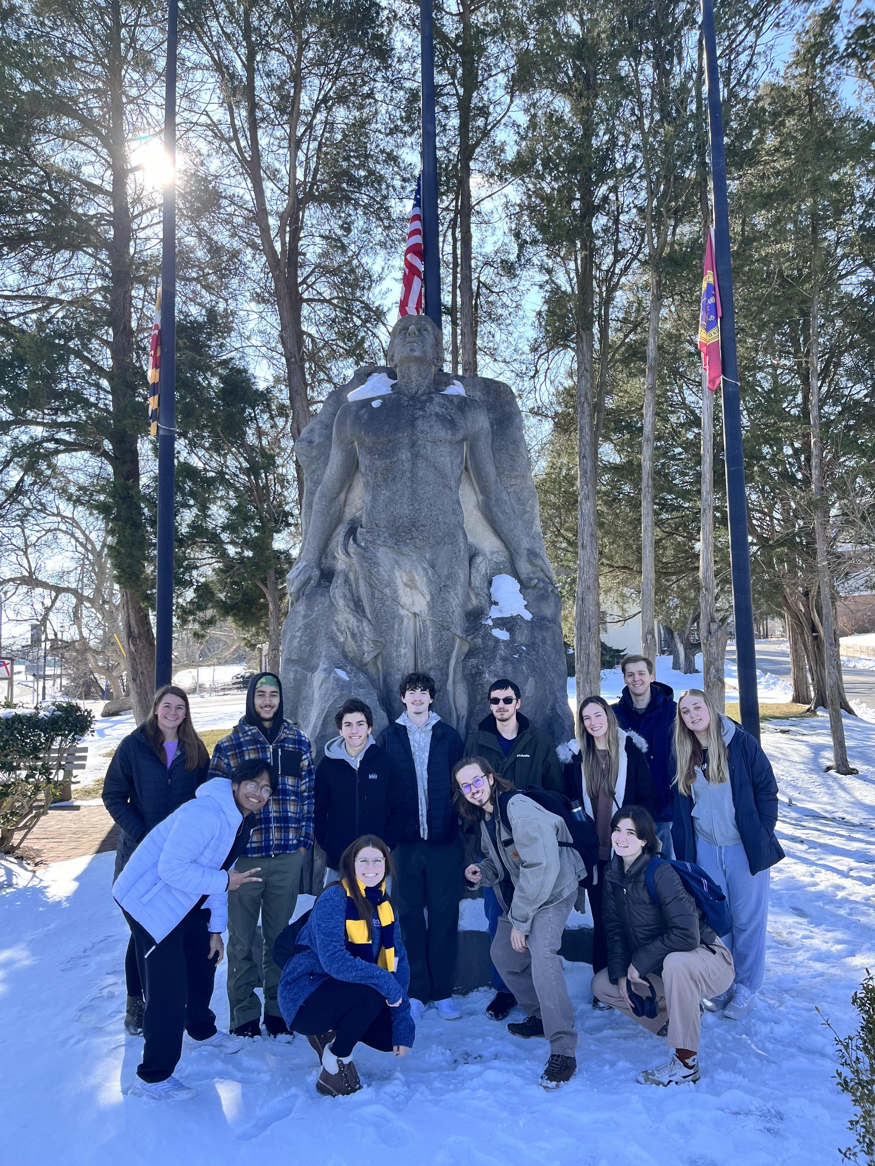 A group of people pose in front of a statue 