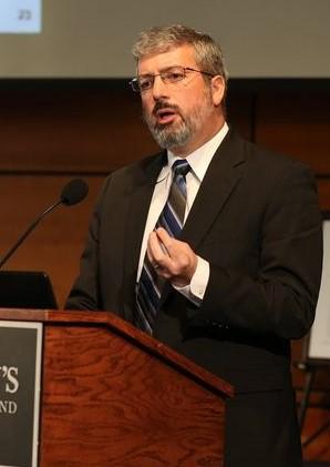 Man in black suit speaking at podium