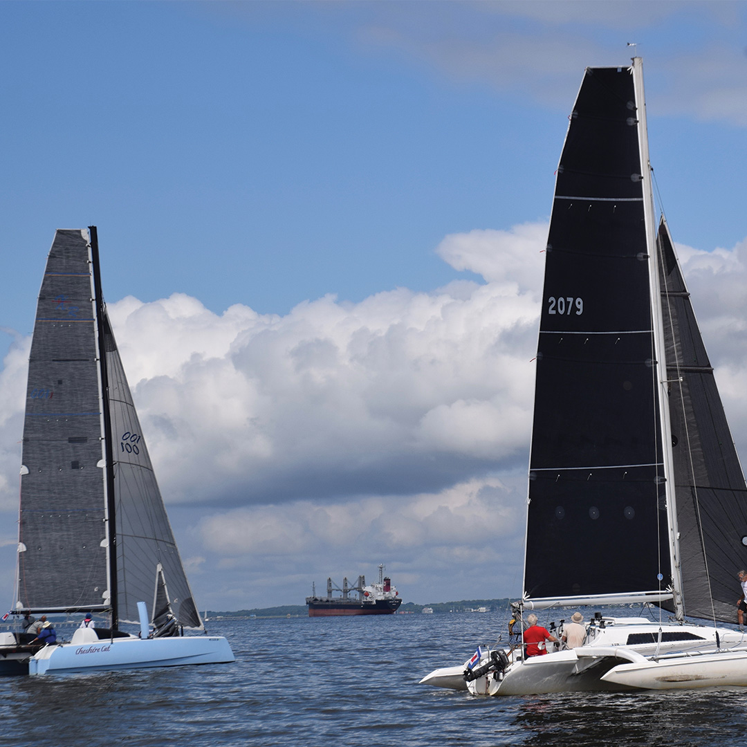 Two sailboats with tall, dark sails 