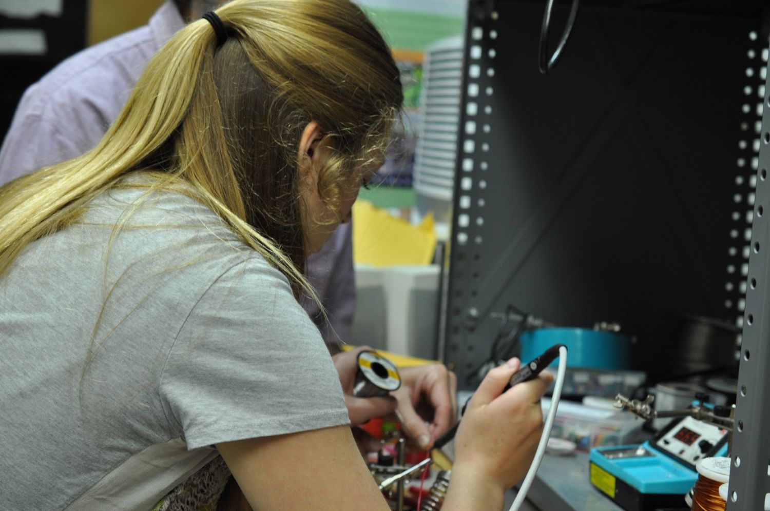 St. Mary's student working on an electronic circuit board at a workstation with various electronic equipment visible.