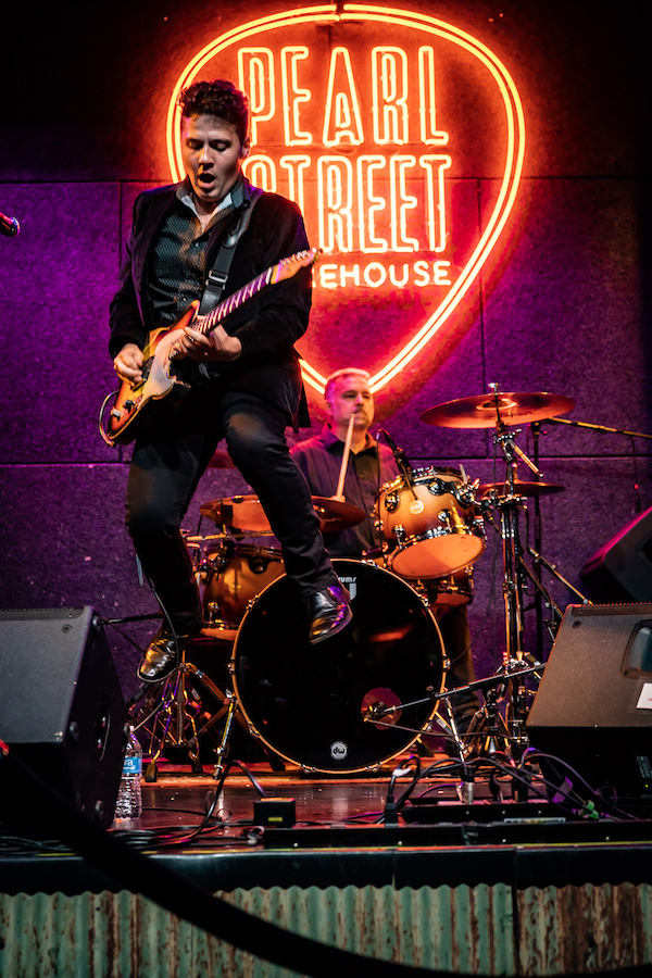 Gabe Stillman playing guitar on stage in front of drums