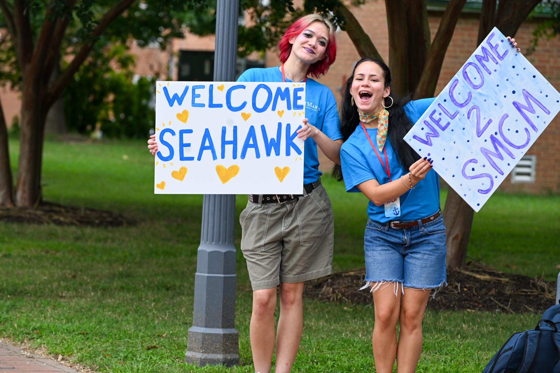 Two St. Mary's College of Maryland students holding up signs that say ;Welcome Seahawk; and ;Welcome to SMCM;