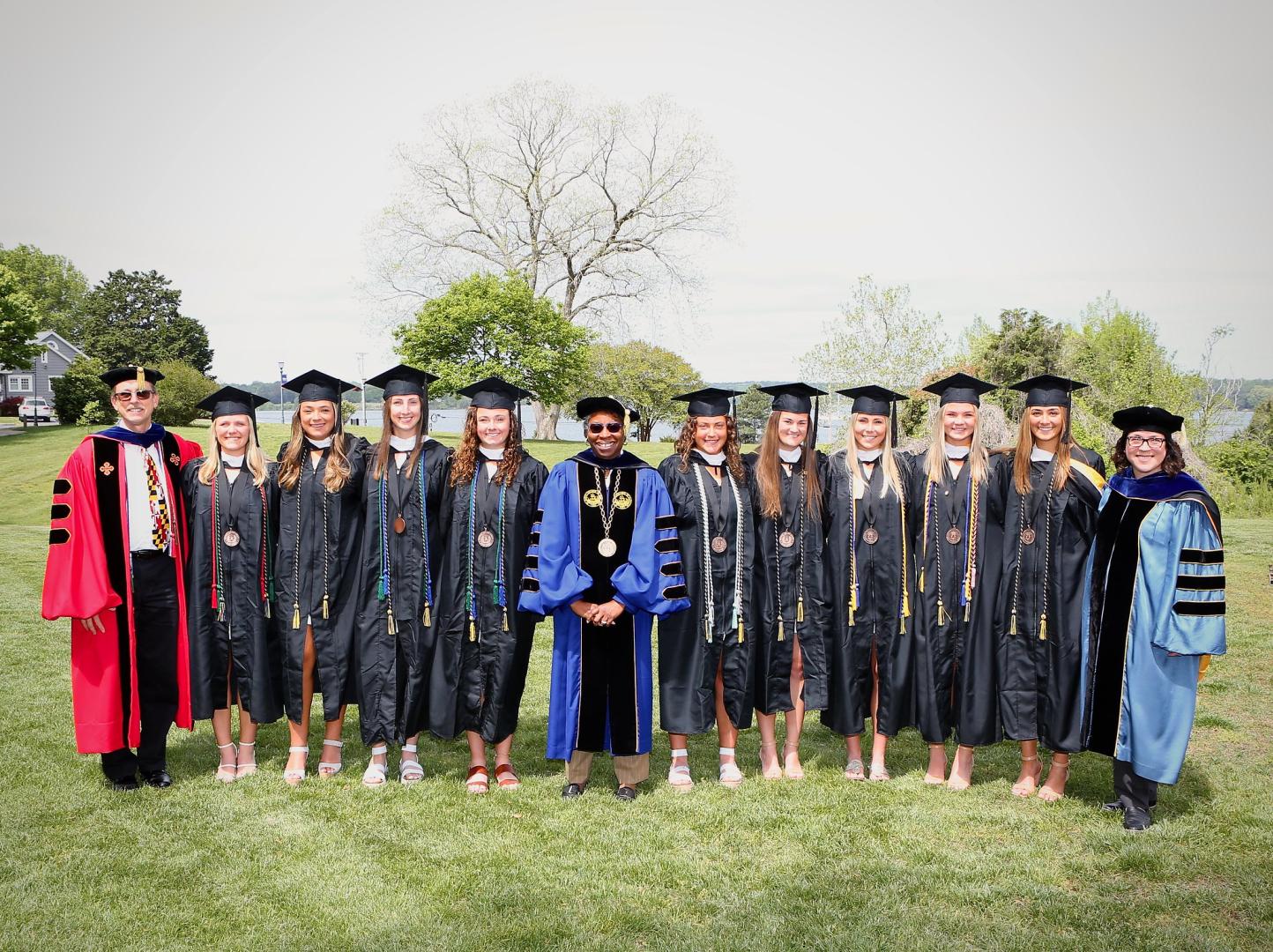 Graduates pose for photo with President Jordan on Townhouse Green 