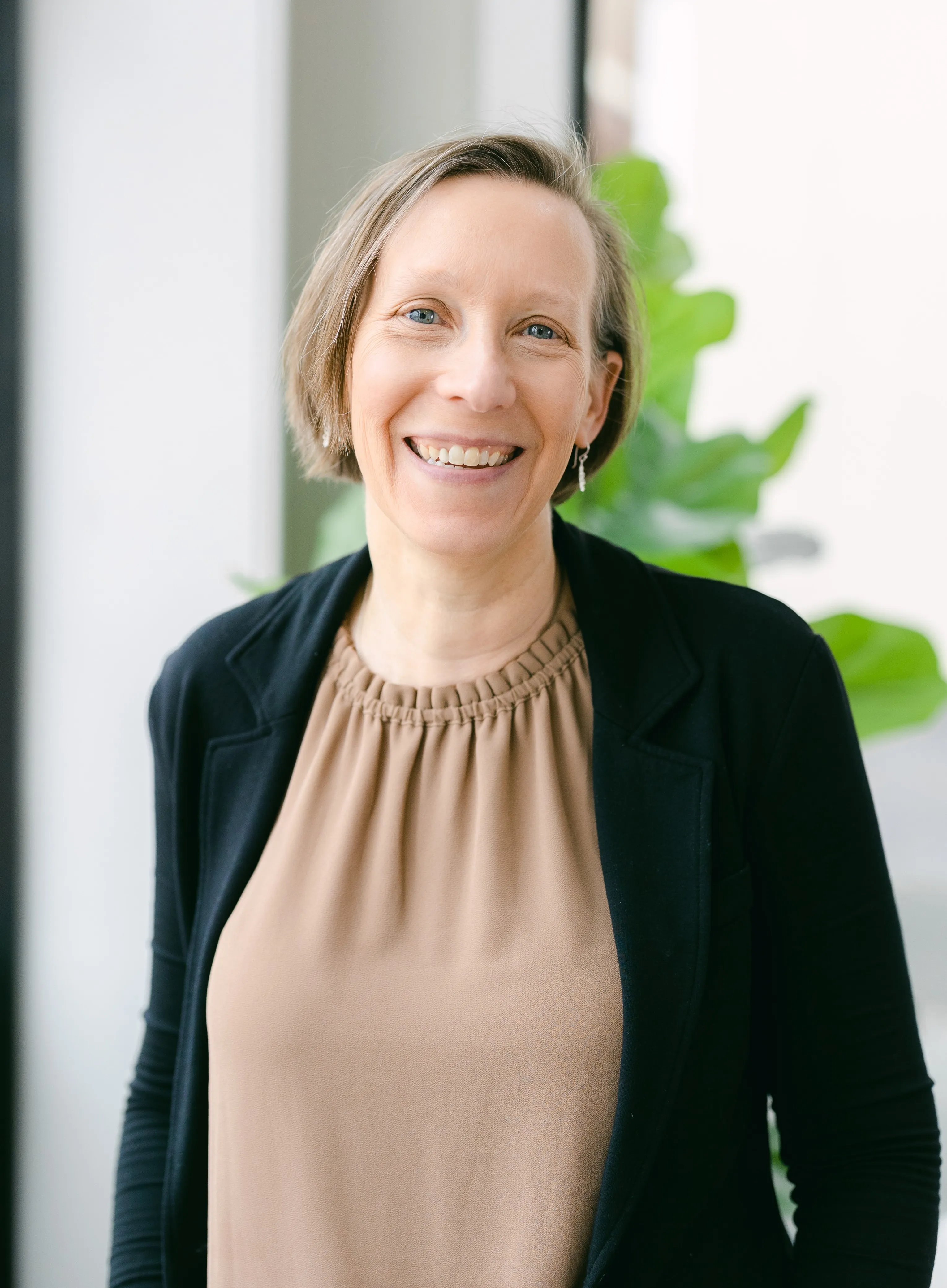 A woman with short hair smiles joyfully.