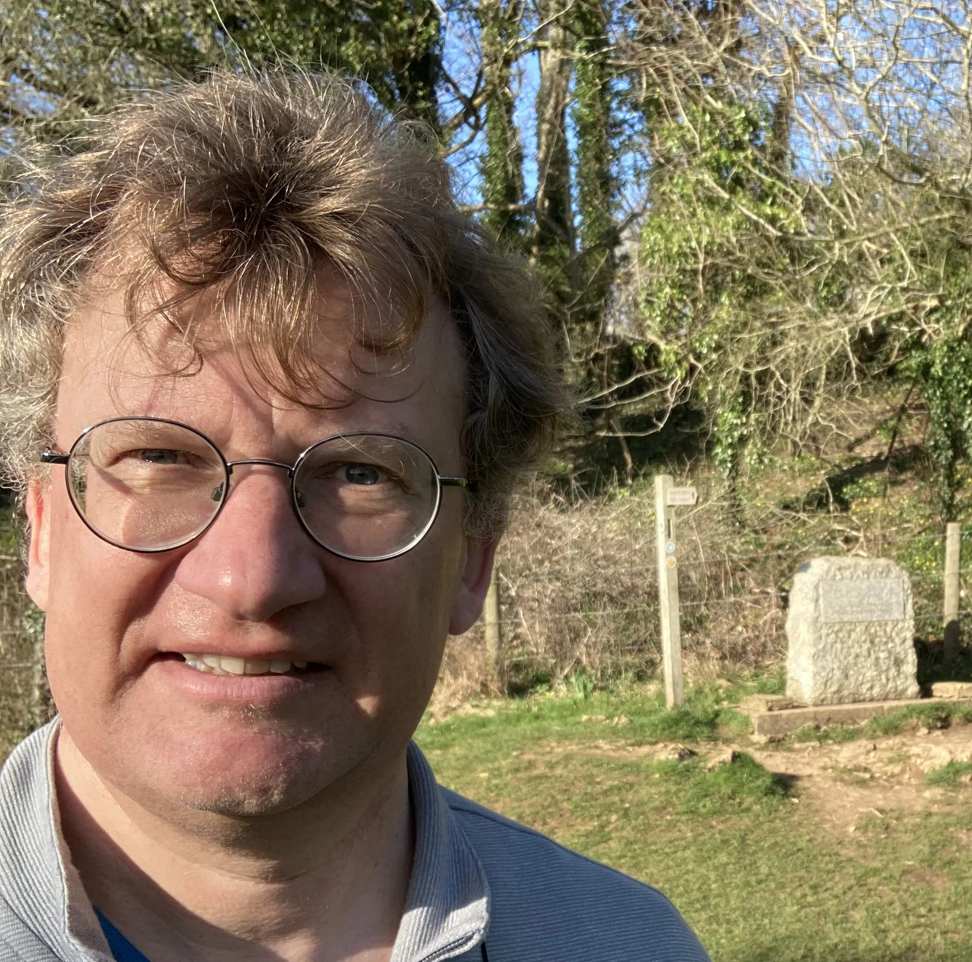 A man wearing glasses is outside smiling.
