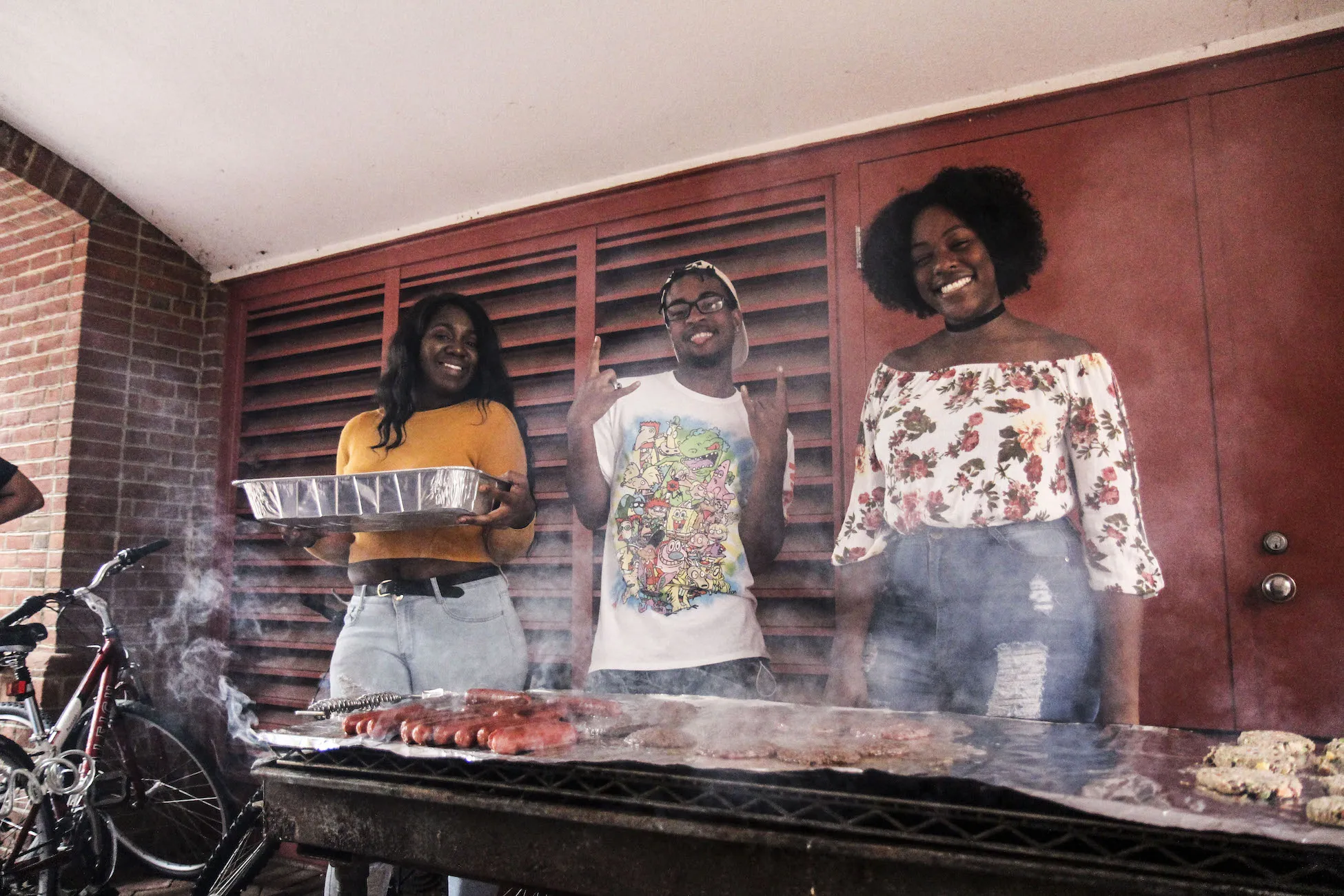 Three students in front of a grill