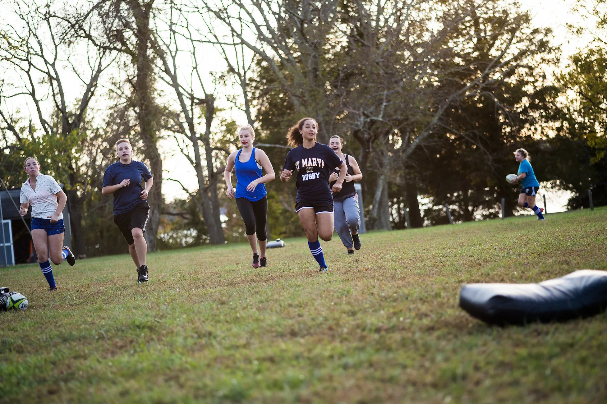 Several Students running on a field with a rugby ball