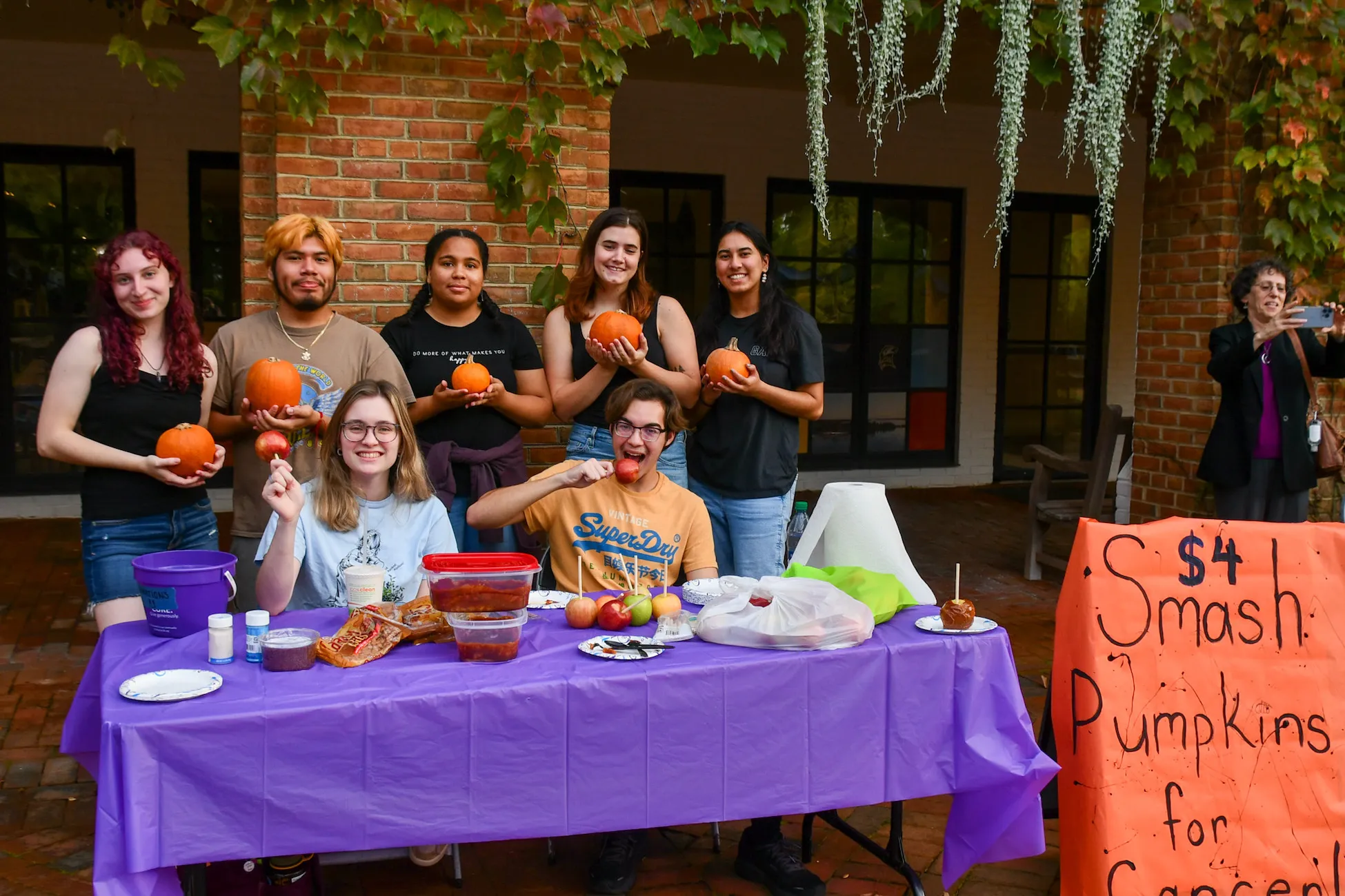 Several students in front of a table holding pumpkins