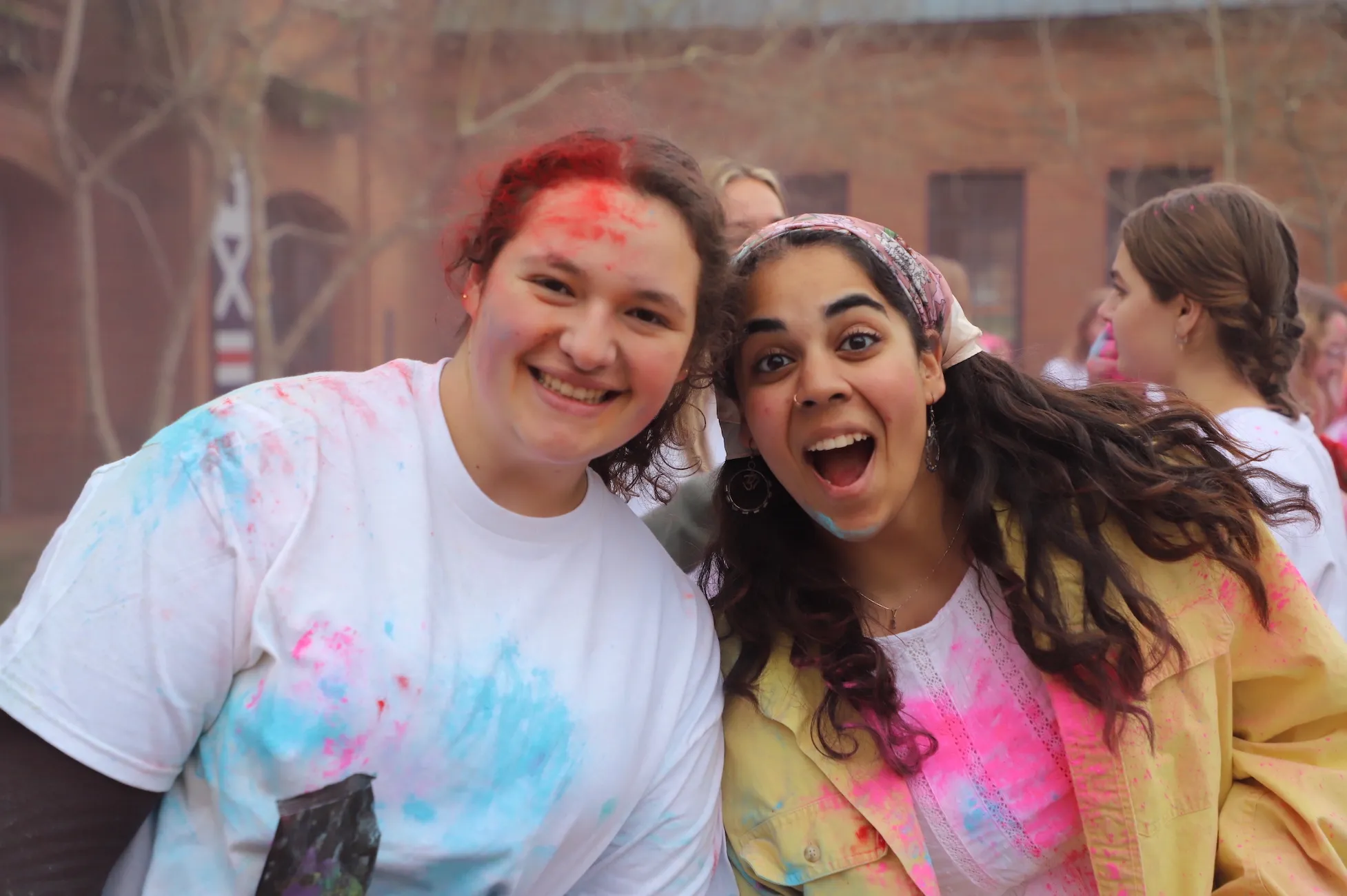Two students posing happily covered in colored chalk