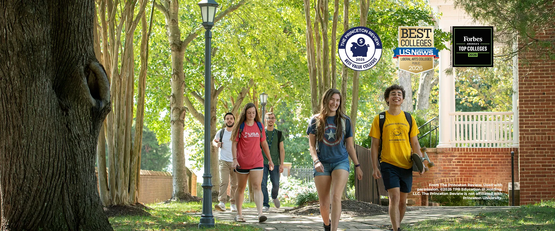A group of college students walk along a campus sidewalk lined with trees and lampposts; college ranking badges appear on the image's right side.