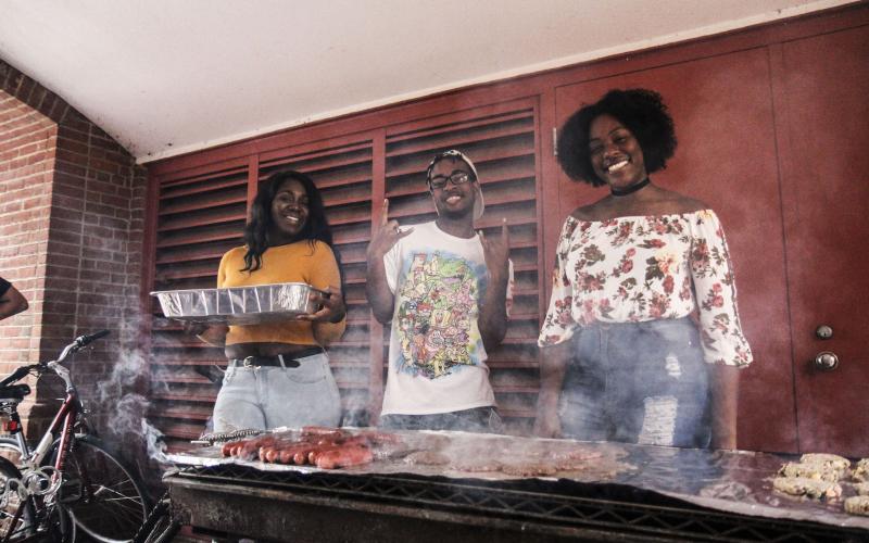 Three students in front of a grill