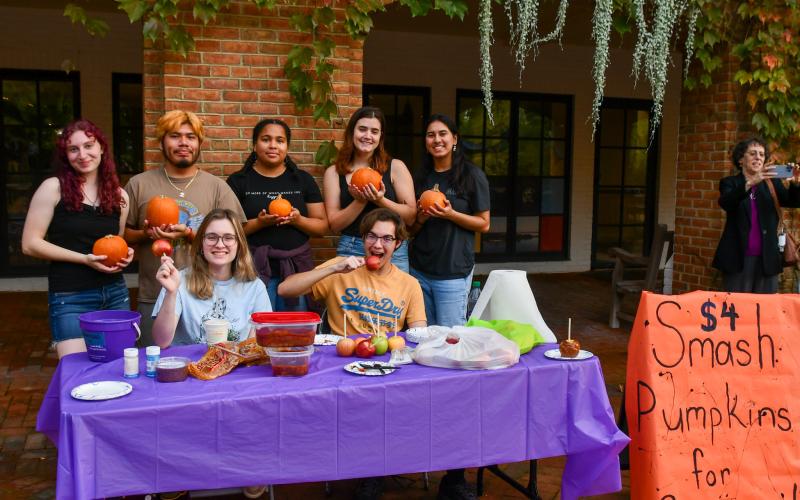 Several students in front of a table holding pumpkins