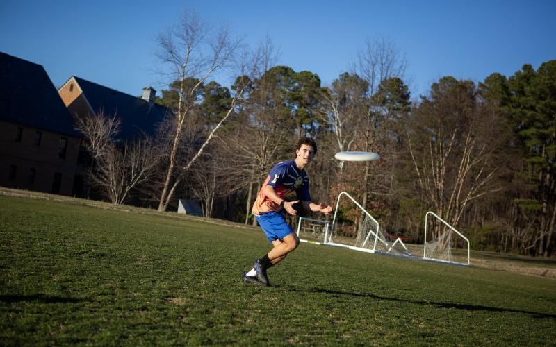 A student in a field throwing a frisbee