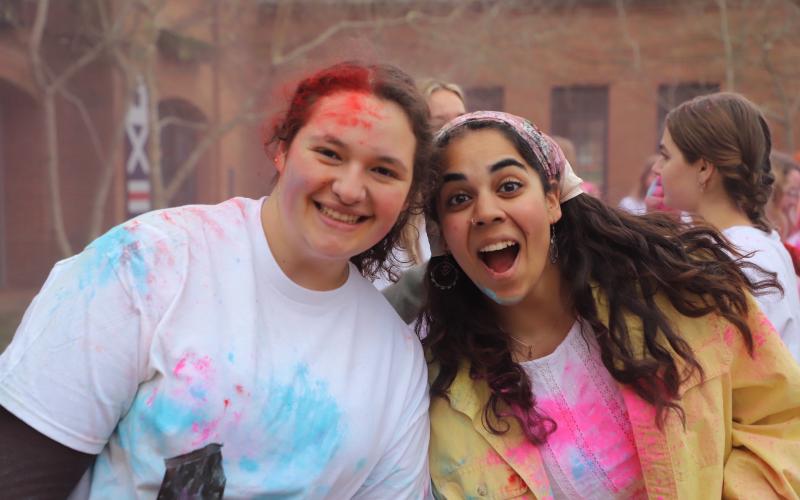 Two students posing happily covered in colored chalk