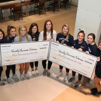 Varsity Women's Lacrosse team holding winning checks