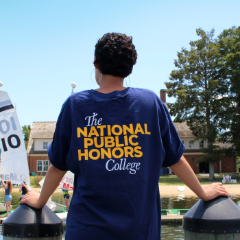 student facing riverfront with national public honors college tee shirt