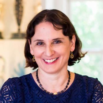 A woman with a blue lace top smile happily.