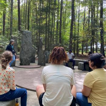 Students sitting around an outdoor sculpture at Annmarie Garden 