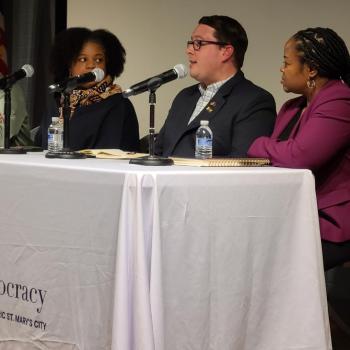 Four people sit at a table with microphones during a panel discussion at the Center for the Study of Democracy.