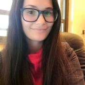 A woman with glasses is smiling in an office