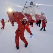 Christina standing on the ice at the North Pole in front of the US Coast Guard Cutter Healy 