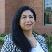 A woman wearing formal attire and having long dark hair is outside.