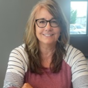 Person with long brown hair and glasses