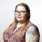 A woman with a patterned sleeveless shirt looks towards the camera.