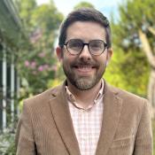 Portrait of Brian Smithson against a background of flowers and trees.
