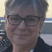 Profile of a woman wearing glasses, smiling.
