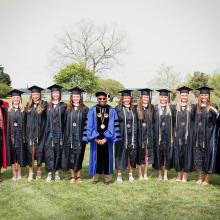 Graduates pose for photo with President Jordan on Townhouse Green 