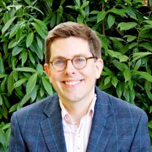 Portrait of Assistant Professor of Anthropology Brian Smithson in front of vegetation