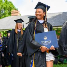 Graduates in cap & gown carrying diplomas