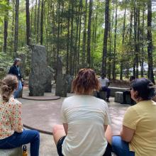Students sitting around an outdoor sculpture at Annmarie Garden 