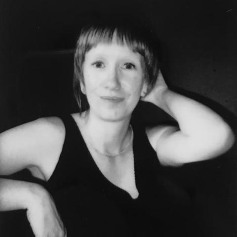 Black and white image of white woman smiling, black background.