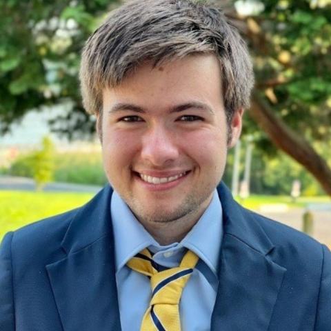 A man wearing formal attire smiles.