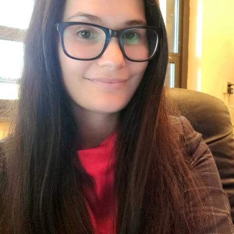 A woman with glasses is smiling in an office