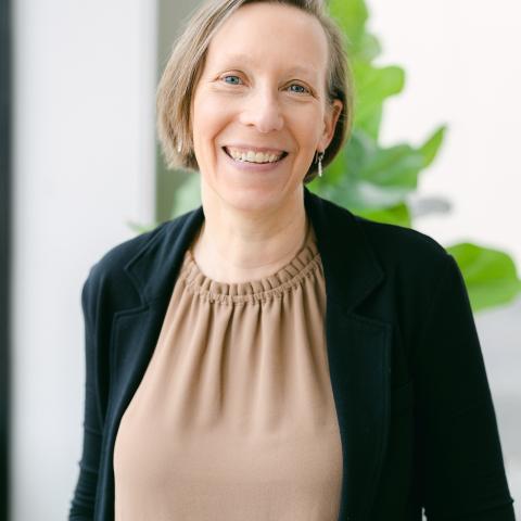 A woman with short hair smiles joyfully.
